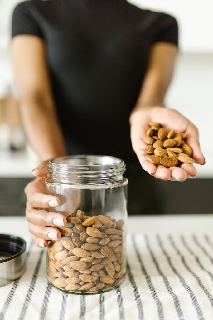 Person Holding Almonds and a Glass Jar