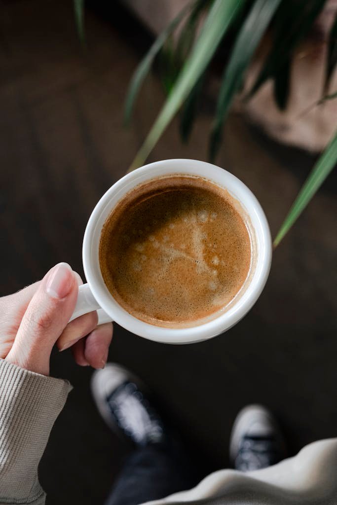 A person holding a cup of coffee in their hand